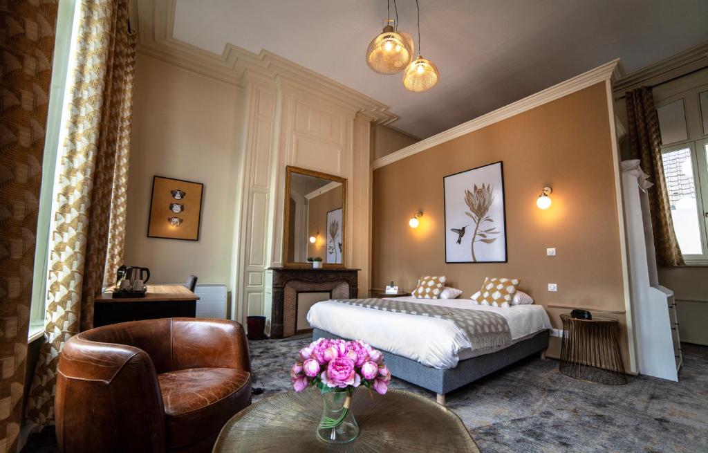 Cette chambre comprend un lit et une table fleurie. dans l'établissement Logis Hôtel & Restaurant - Les Hauts de Montreuil, à Montreuil-sur-Mer