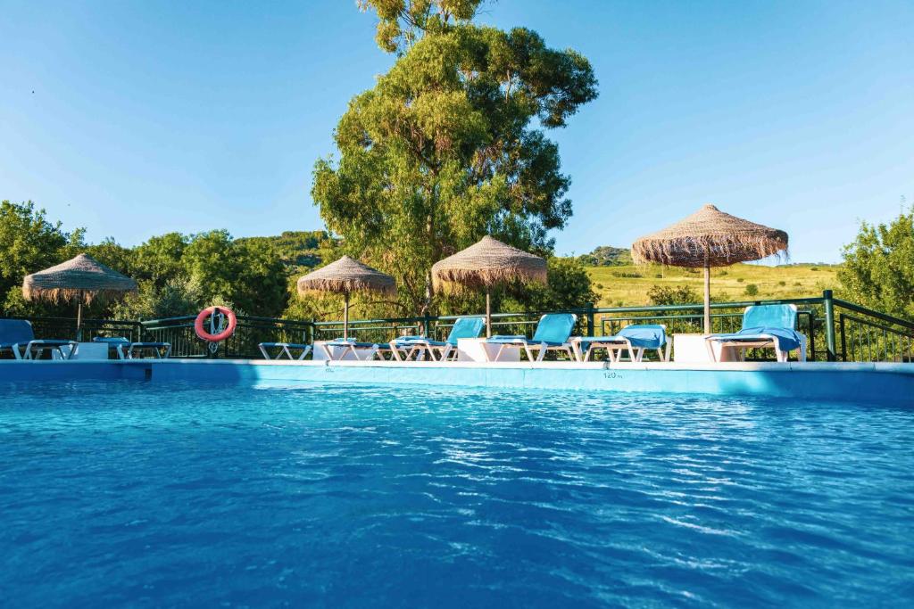 a swimming pool with chairs and umbrellas at El Horcajo in Montecorto