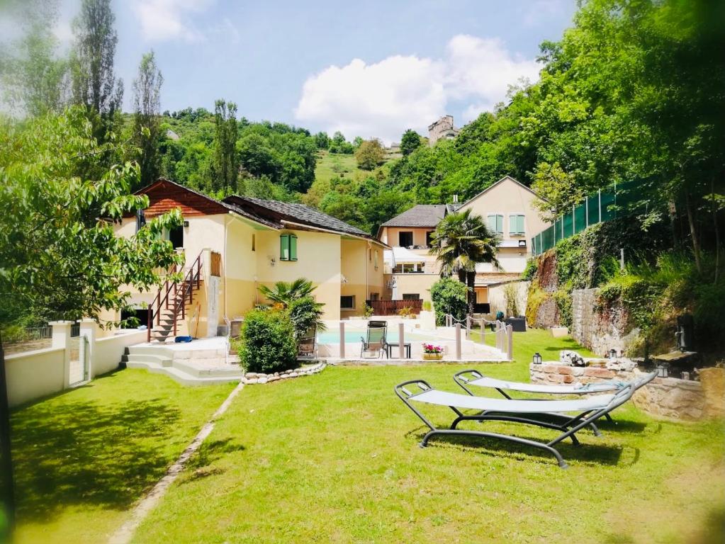 a house with a yard with two benches in the grass at Les Gîtes du Moulin d Olt in La Canourgue