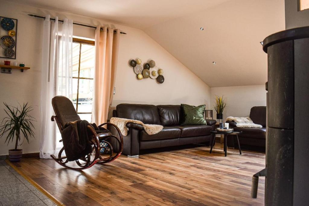 a living room with a black leather couch and aokedokedoked at Ferienwohnung bei Wolf und Eule in Lohberg