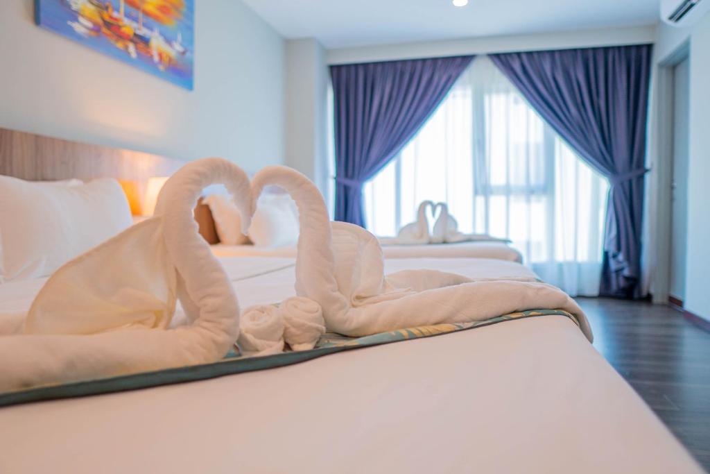 dois cisnes feitos de toalhas numa cama em FLYPOD Hotel em Kota Kinabalu
