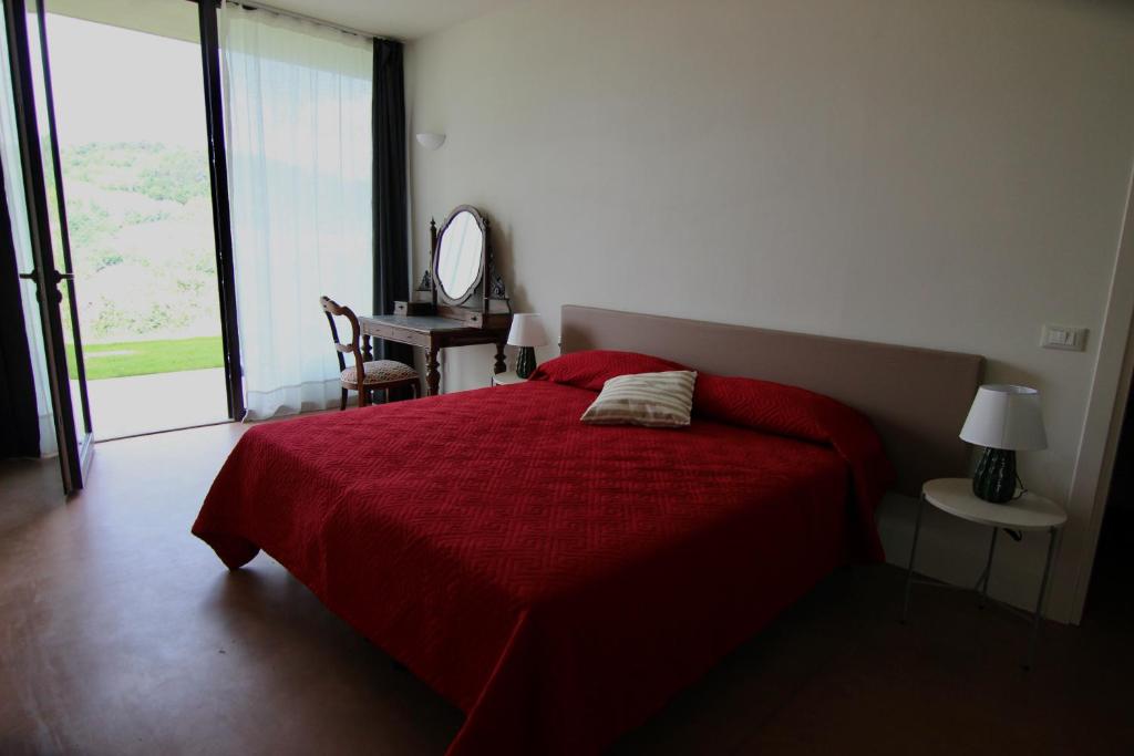 sypialnia z czerwonym łóżkiem i lustrem w obiekcie Relais Mevigo - Casa Padronale w mieście Casola Valsenio