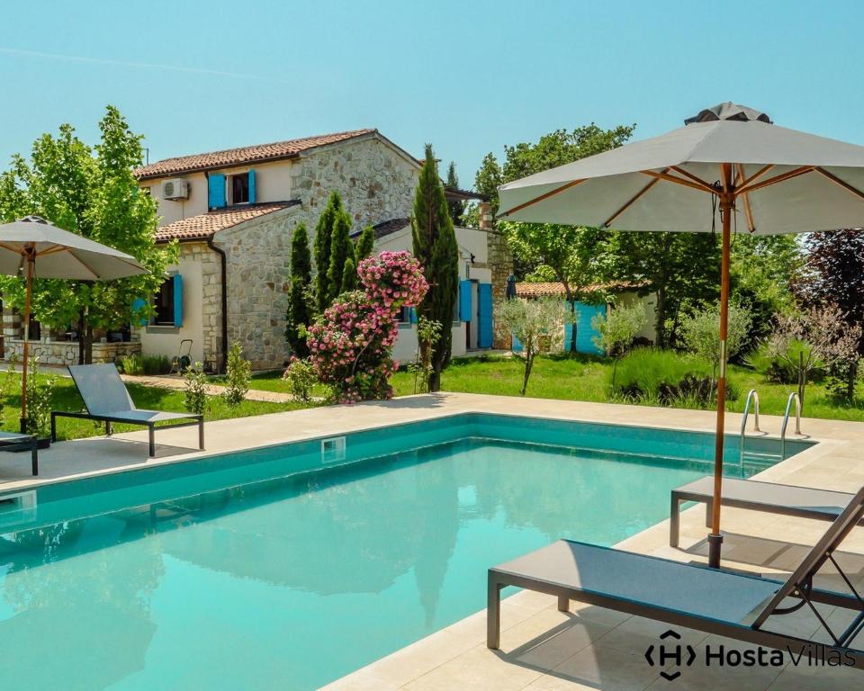 een zwembad met 2 stoelen en een parasol bij Villa Cypress by Istrian Country Houses in Babići