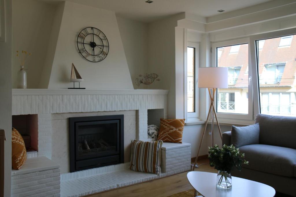 sala de estar con chimenea y reloj en la pared en Salt&Sea, en Middelkerke