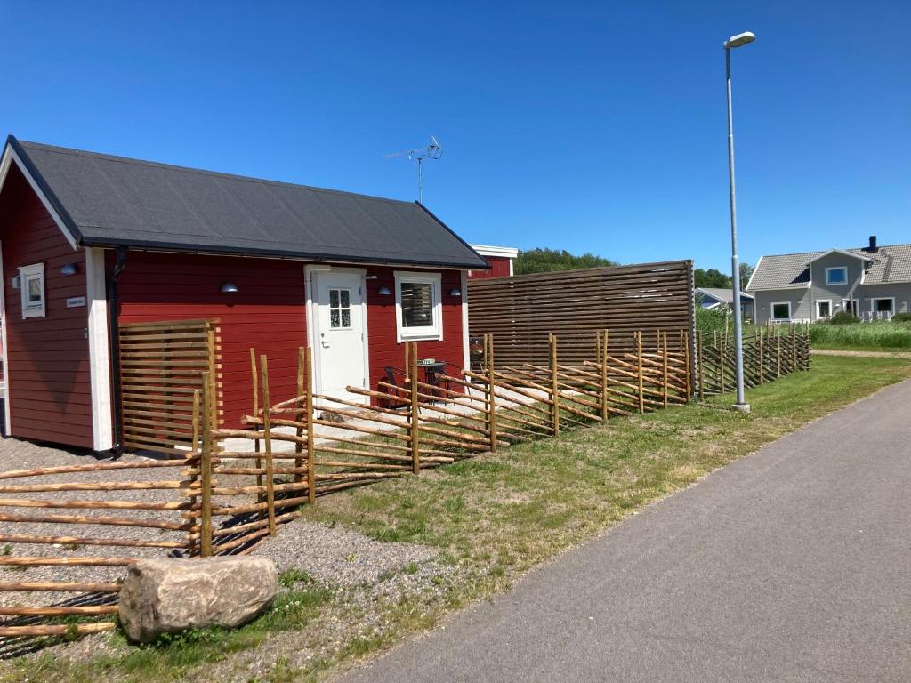 a red building with a fence next to a house at Smeakallesbod in Tvååker