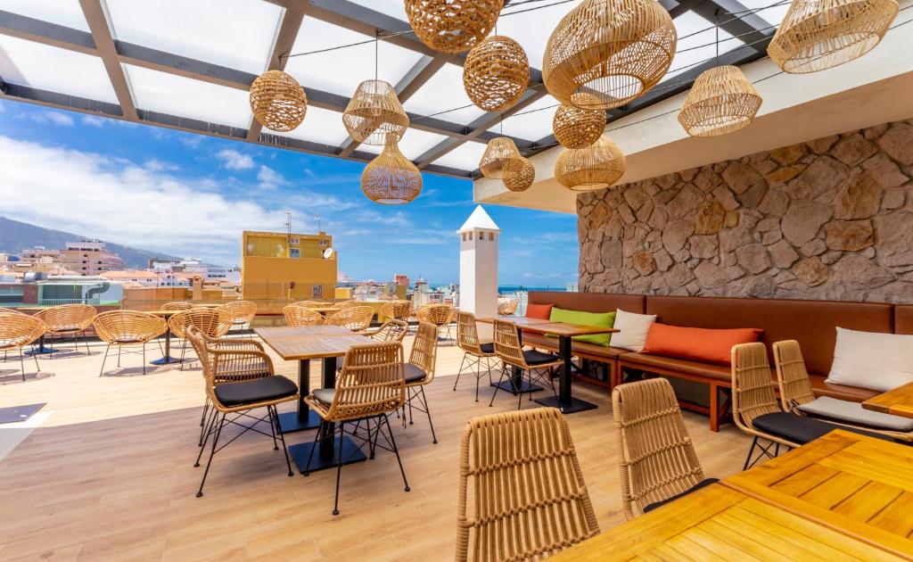 um restaurante no último piso com mesas e cadeiras e vista em DWO Nopal em Puerto de la Cruz