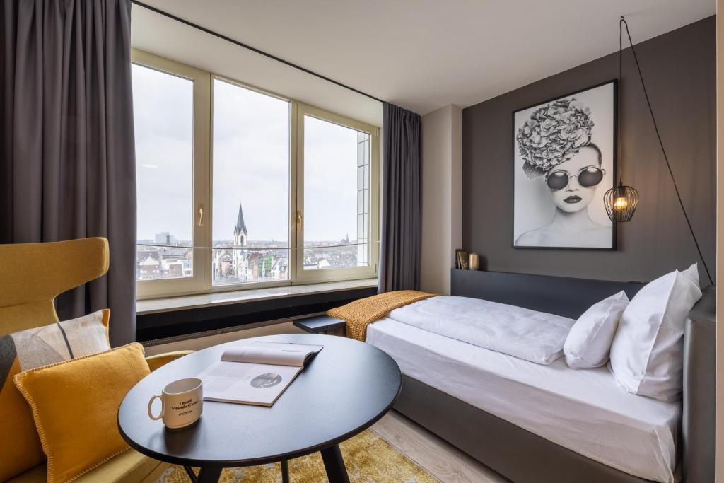 a hotel room with a bed and a table and window at JOYN Cologne - Serviced Apartments in Cologne