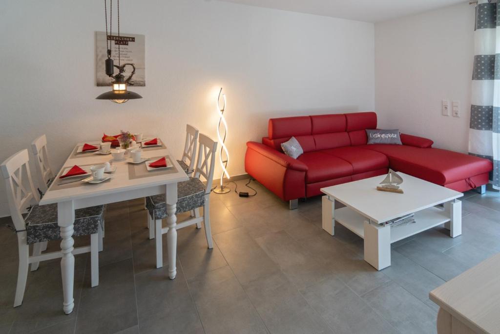 un soggiorno con divano rosso e tavolo di Lieblingsplatz a Dornumersiel