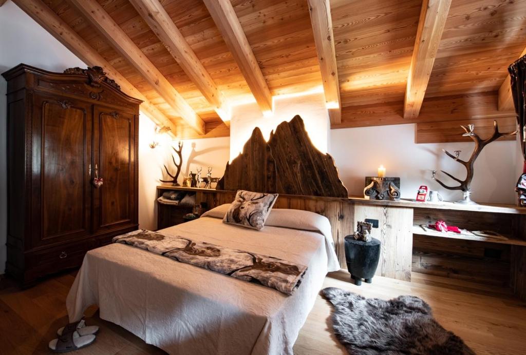 a bedroom with a bed in a room with wooden ceilings at Dolomiti Chalet degli Abeti in Campitello di Fassa