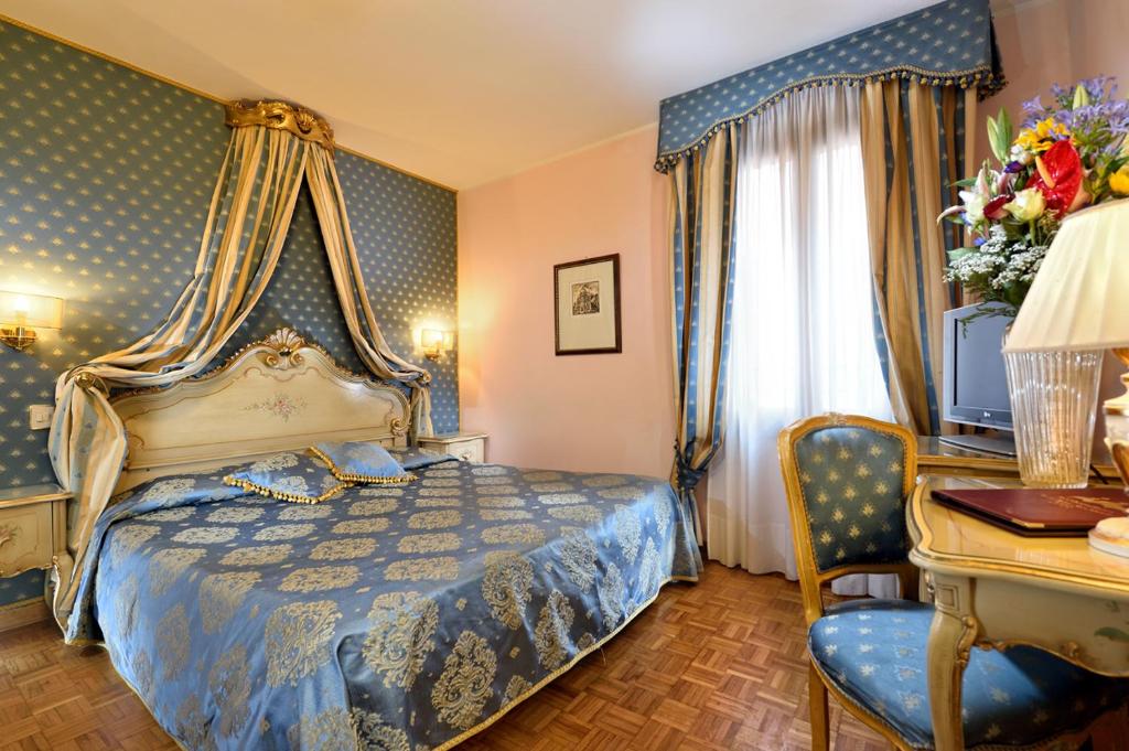 a bedroom with a blue bed and a desk with a computer at Royal San Marco Hotel in Venice