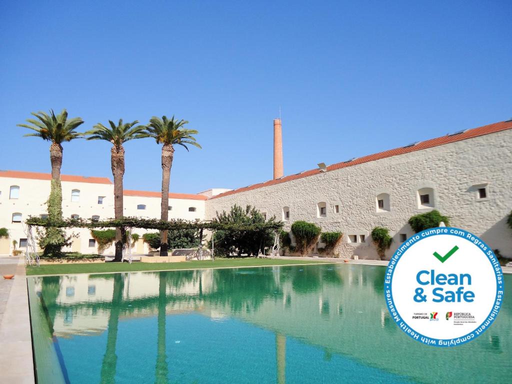 a swimming pool in front of a building with palm trees at Architect Arts Elegant Villa in Tavira
