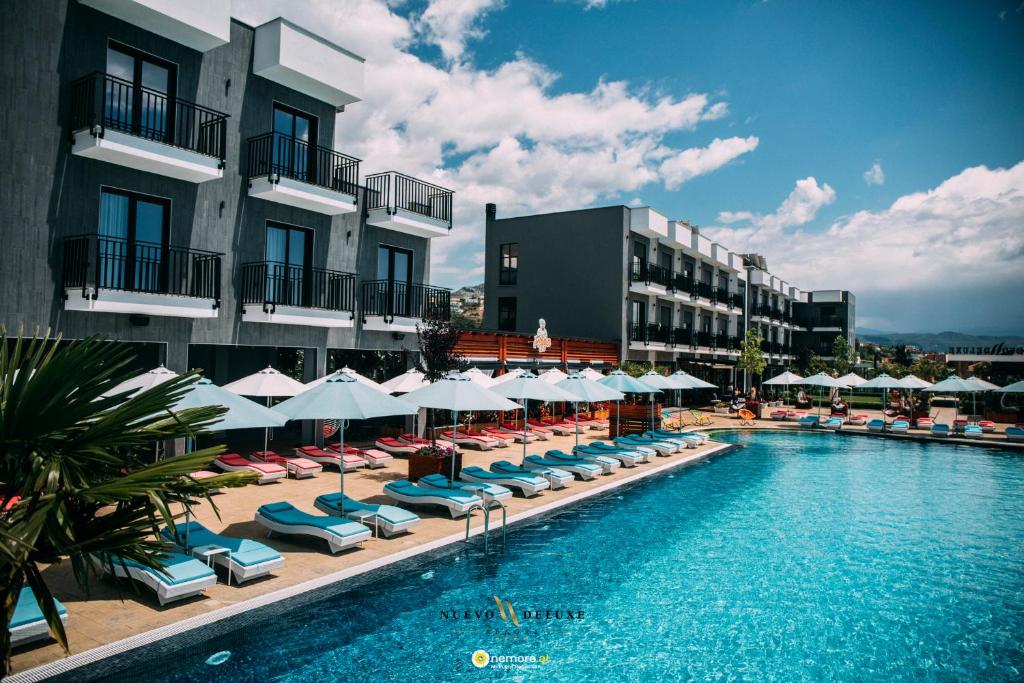 a swimming pool with chairs and umbrellas next to a building at Nuevo Deluxe in Shëngjin