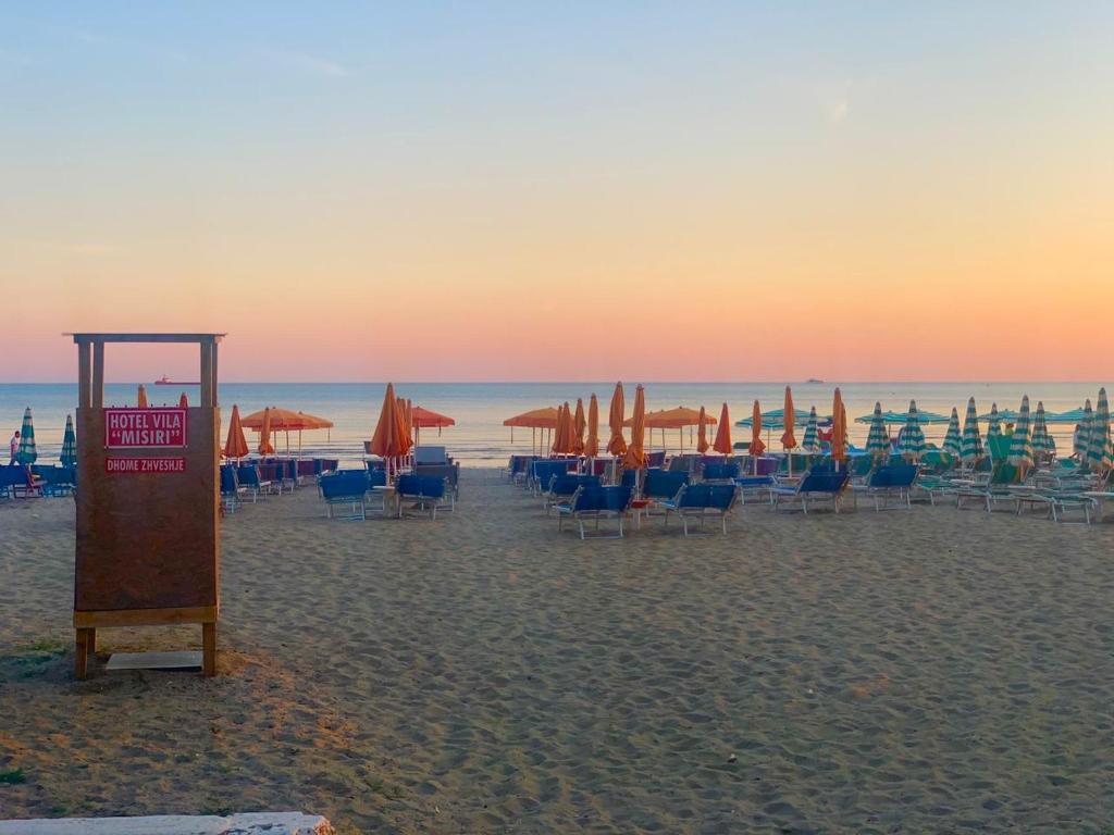 un grupo de sillas y sombrillas en una playa en Hotel Vila Misiri en Durrës