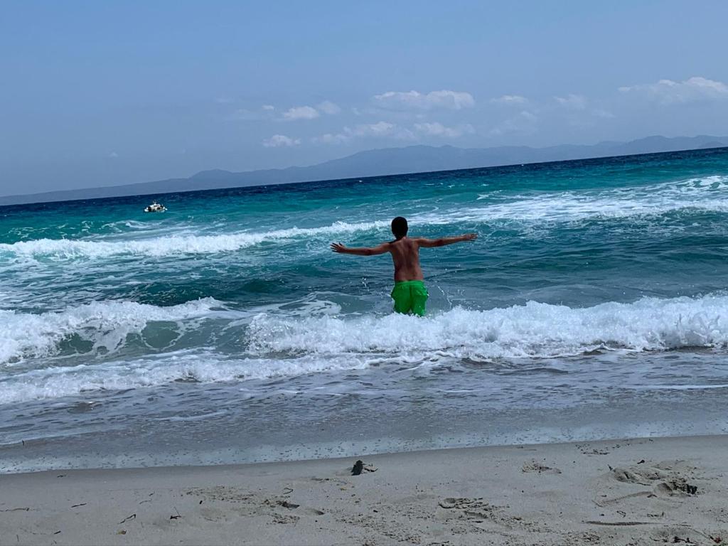 un hombre parado en el agua en la playa en Villa Evita , penthouse, 53m2 ,Athytos 450m from the beach, en Afitos