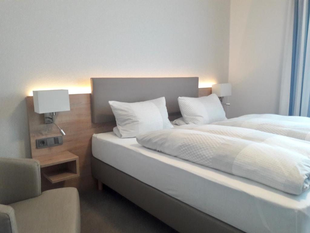 een slaapkamer met een bed met witte lakens en kussens bij Pension Dirkschnieder in Schloß Holte-Stukenbrock