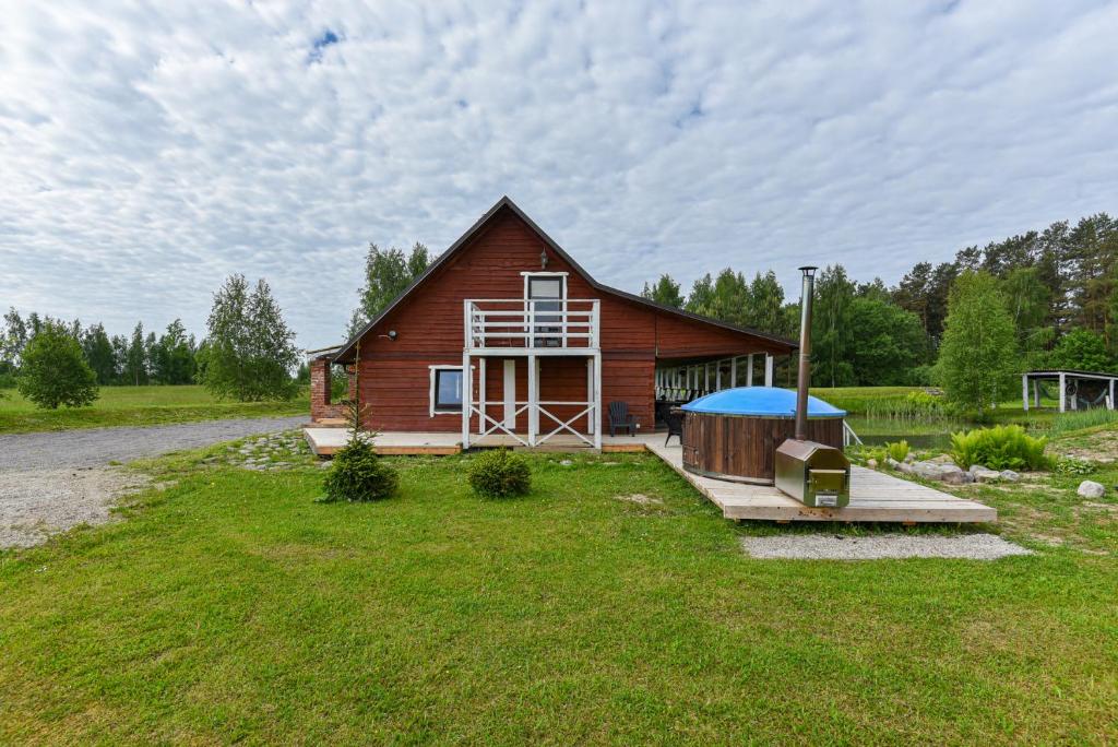 a large wooden house with a gazebo in the yard at Private house surrounded by woods and lake in Kalviškiai