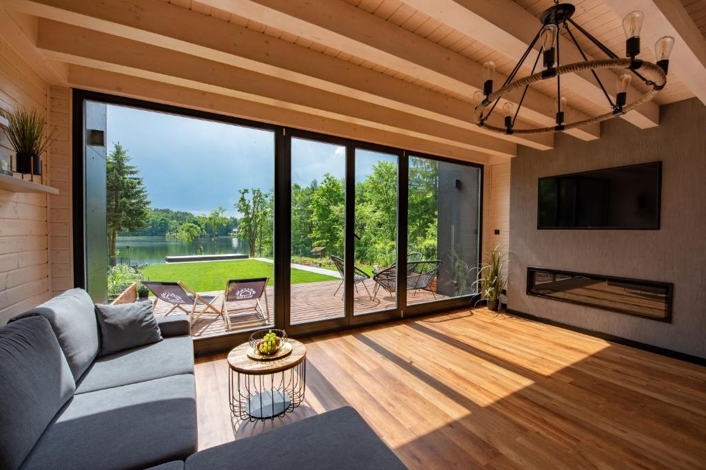 a living room with a couch and a large window at NATERIA DOMEK NAD JEZIOREM in Naterki