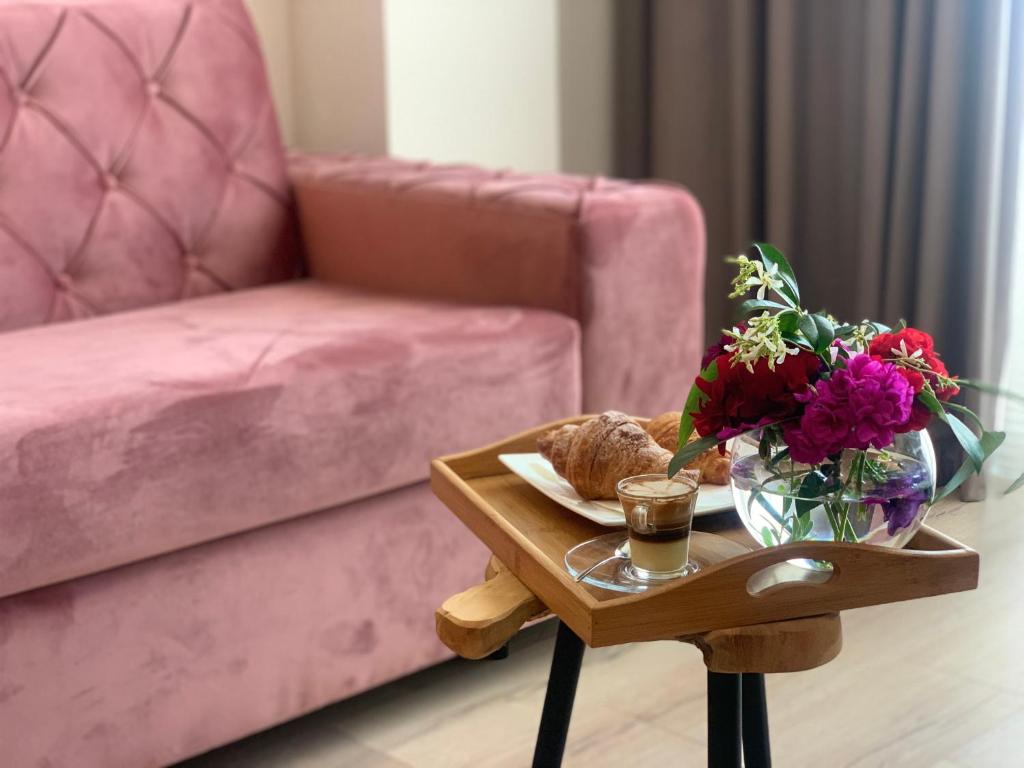 a coffee table with a vase of flowers and a couch at Iliad Hotel in Durrës