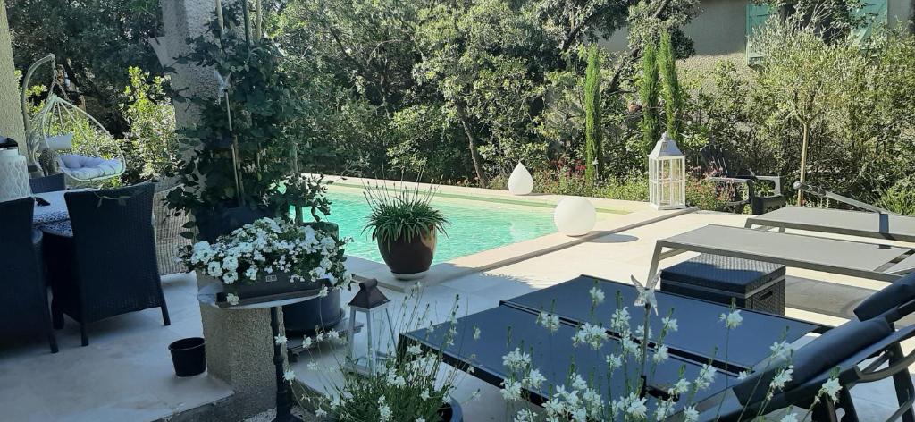 een patio met een zwembad en een tafel en planten bij LA MAISON DU PONT DU GARD in Vers Pont du Gard
