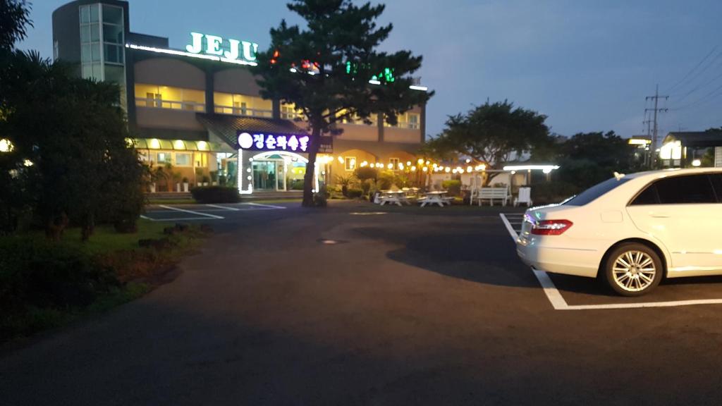 ein weißes Auto, das auf einem Parkplatz vor einem Gebäude parkt in der Unterkunft Jeju Feel House in Jeju-do