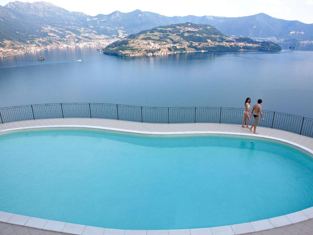 two women standing by a swimming pool with a view of the water at Cherubino - stunning lake view with swimming pool in Parzanica