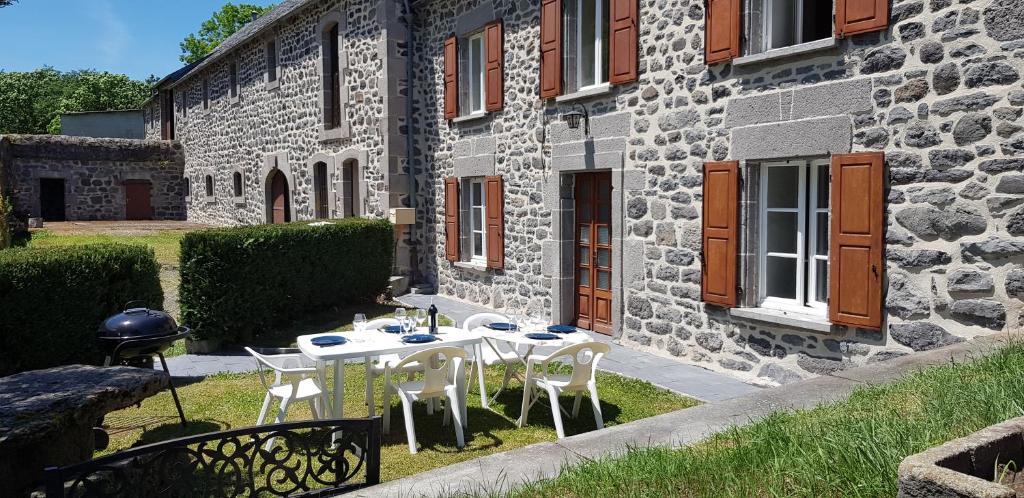 een tafel en stoelen voor een stenen gebouw bij Lodge-Sagne une ferme rénovée au cœur du Cantal à proximité de la station de ski du Lioran 
