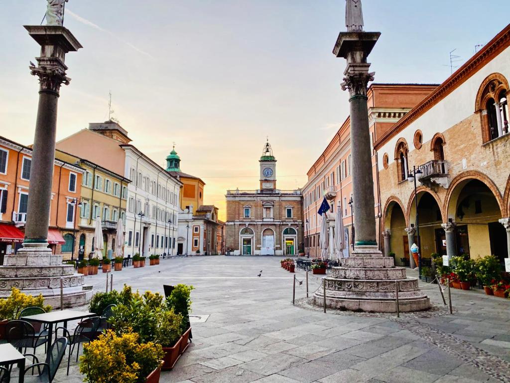 una calle de la ciudad con columnas y un edificio con una torre de reloj en B&B Anastagi, en Rávena