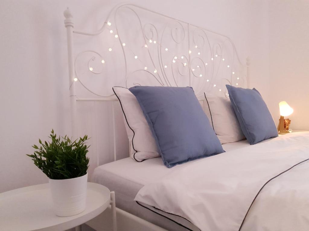 a white bed with blue pillows and a white headboard at Eva Home in Roşiori de Vede