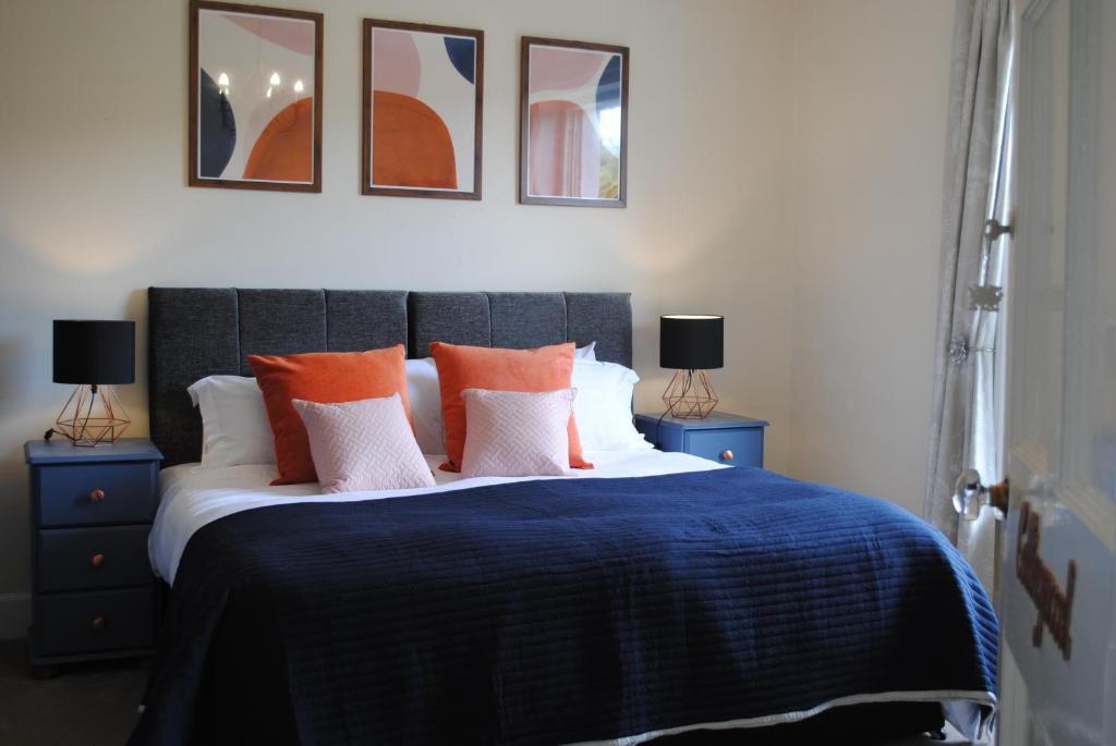 a bedroom with a bed with orange and white pillows at Penygelli Apartments in Newtown