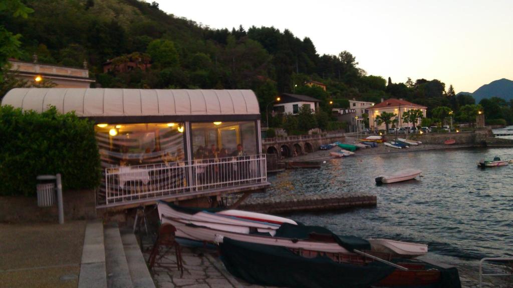 a restaurant on the side of a river with boats at Lago Maggiore in Lesa