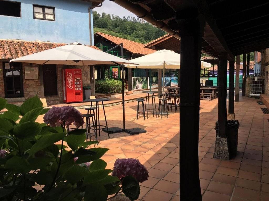 un patio con mesas, sillas y sombrillas en Albergue La Posada Cangas de Onis en Cangas de Onís