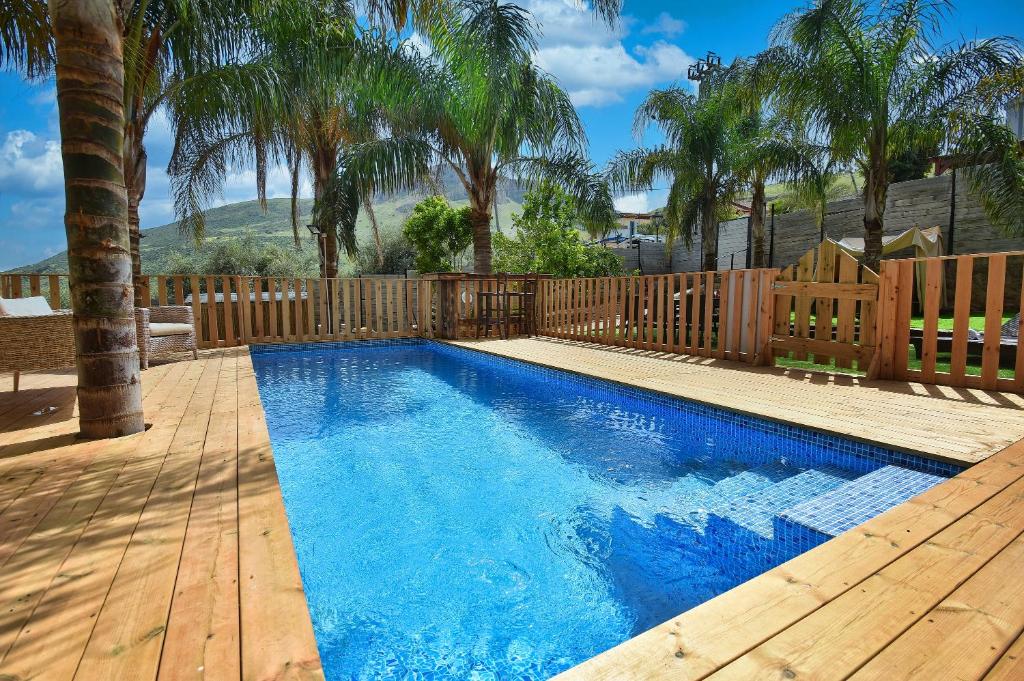 a swimming pool with a wooden deck and a fence at וילה גאיה בכנרת-VIILA GAYA in Migdal