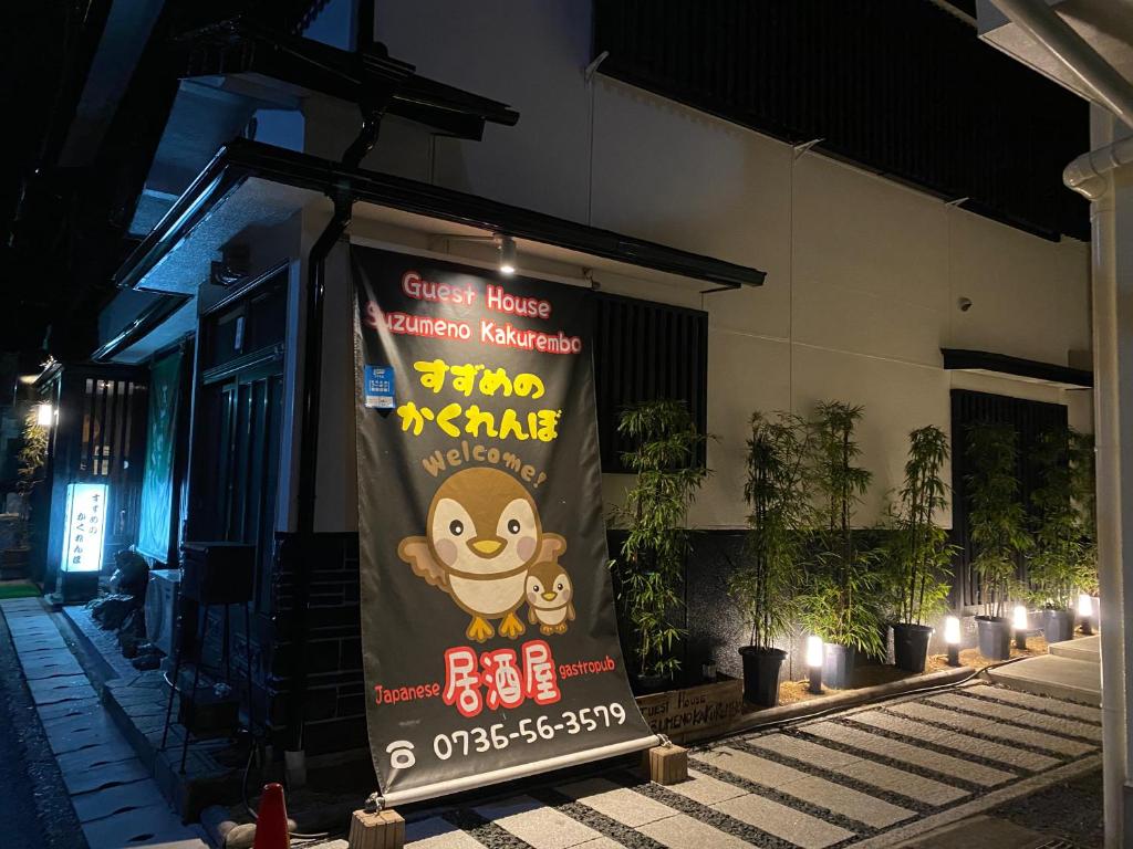 a banner on the side of a building at night at Guest House Suzumeno Kakurembo in Koyasan