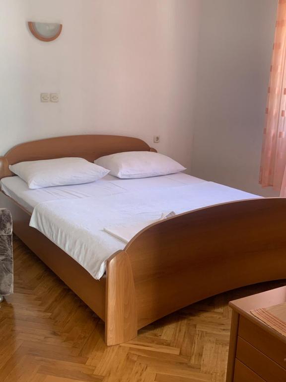 un letto con lenzuola e cuscini bianchi in una camera da letto di APARTMAN ADRIANA a Podaca