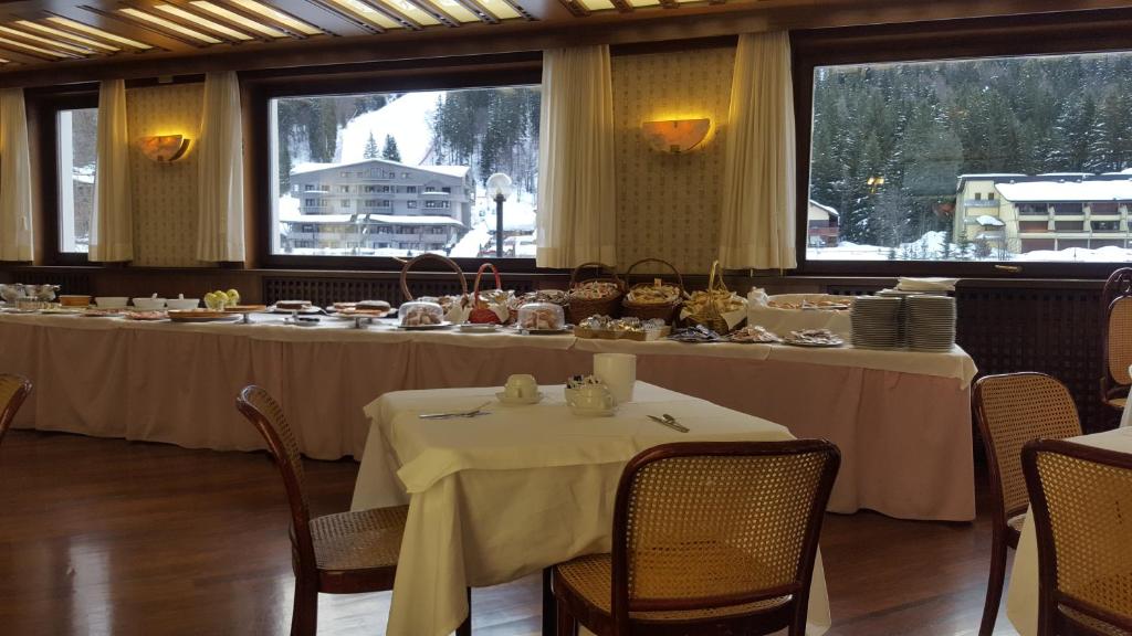 a dining room with two tables with white tablecloths at Hotel Cristallo in Madonna di Campiglio