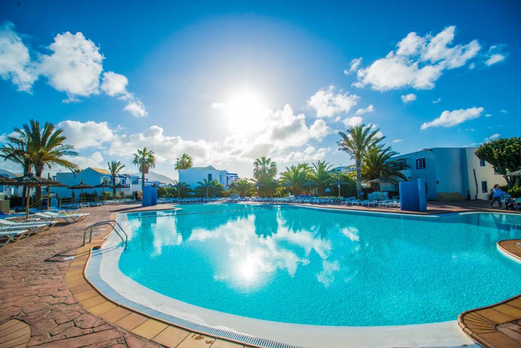 a swimming pool at the resort with palm trees at HL Paradise Island in Playa Blanca