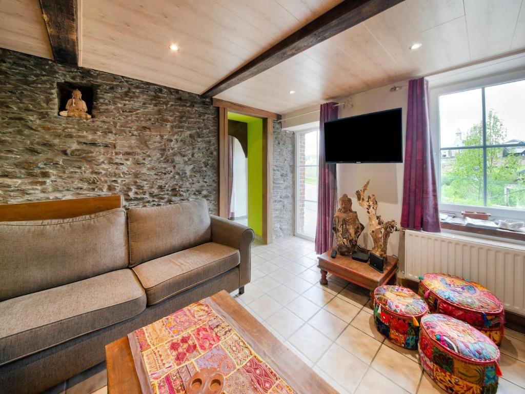 a living room with a couch and a stone wall at Zen inspired Holiday Home in Orchimont with Jacuzzi in Orchimont