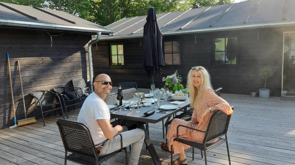 een man en vrouw aan een tafel op een patio bij Sommerhus Mossø in Skanderborg