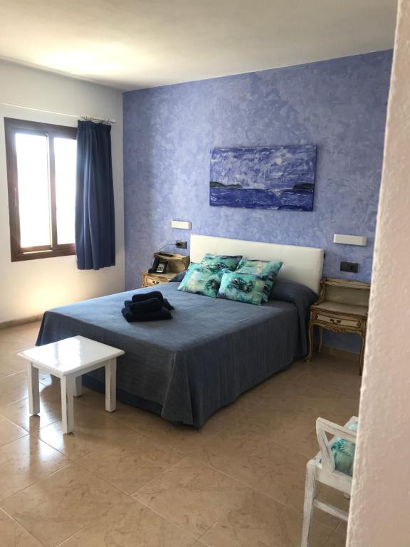 a bedroom with a bed and a table in it at Apartamentos El Bergantin Menorca Club in Fornells
