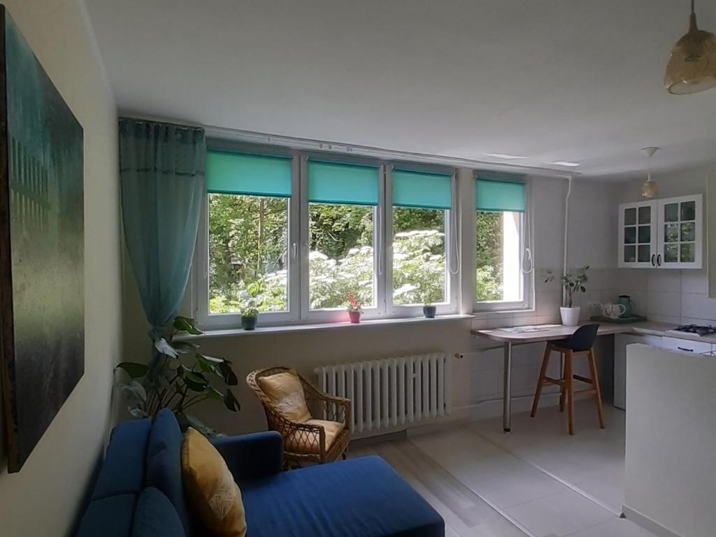 salon z niebieską kanapą i oknami w obiekcie Global Trip Apartament w Tychach