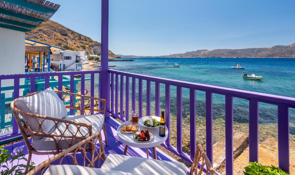 a table and chairs on a balcony with a view of the ocean at The Colourful Land Milos in Klima