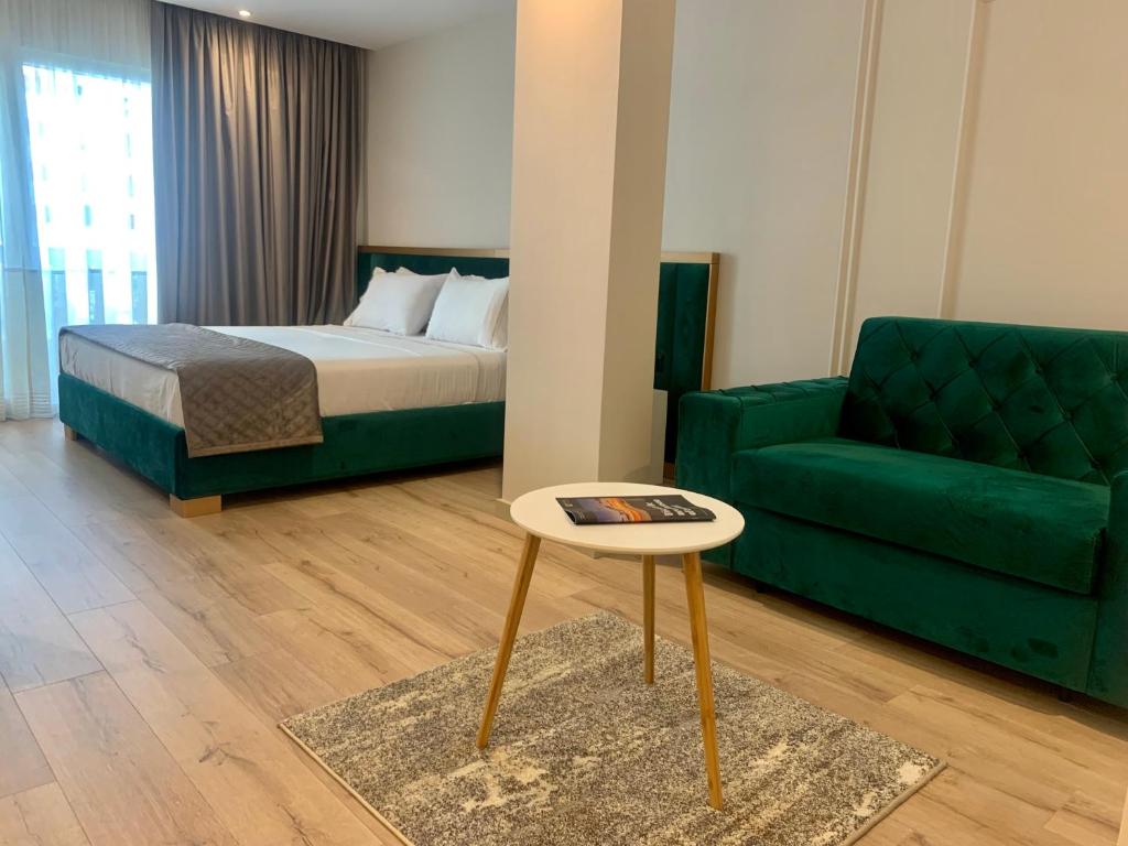 a bedroom with a bed and a couch and a table at Iliad Hotel in Durrës