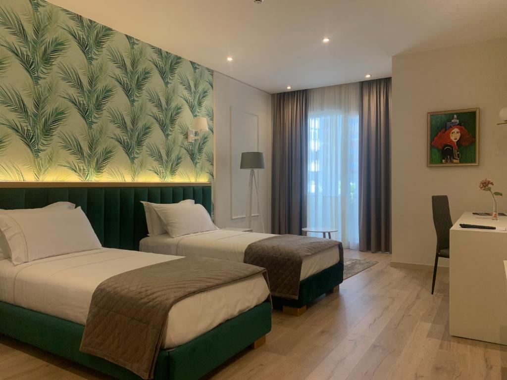 two beds in a hotel room with a mural on the wall at Iliad Hotel in Durrës