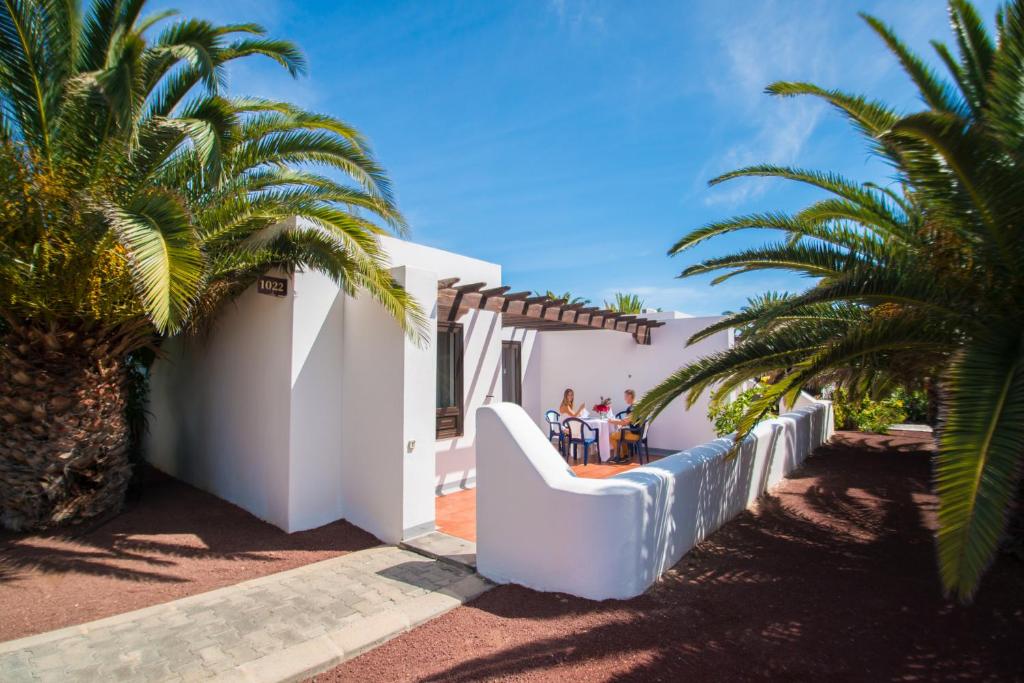 uma casa branca com palmeiras em frente em HL Rio Playa Blanca em Playa Blanca