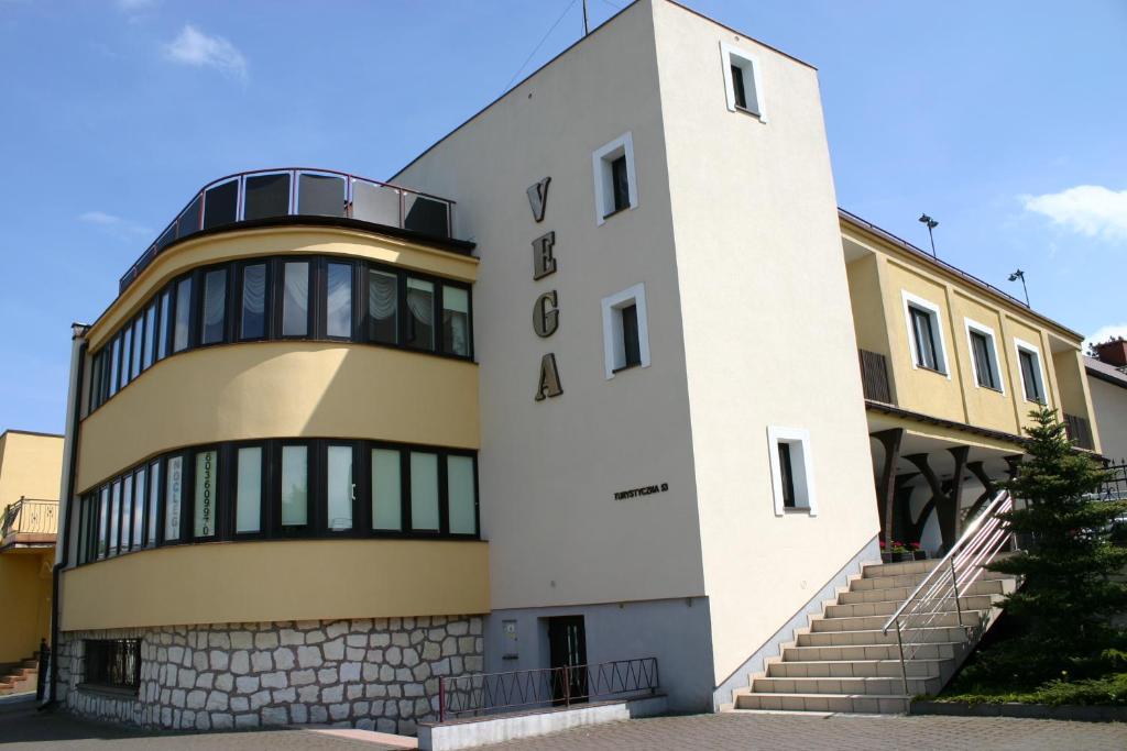 un edificio blanco y amarillo con escaleras delante en Apartamenty Vega, en Charzykowy