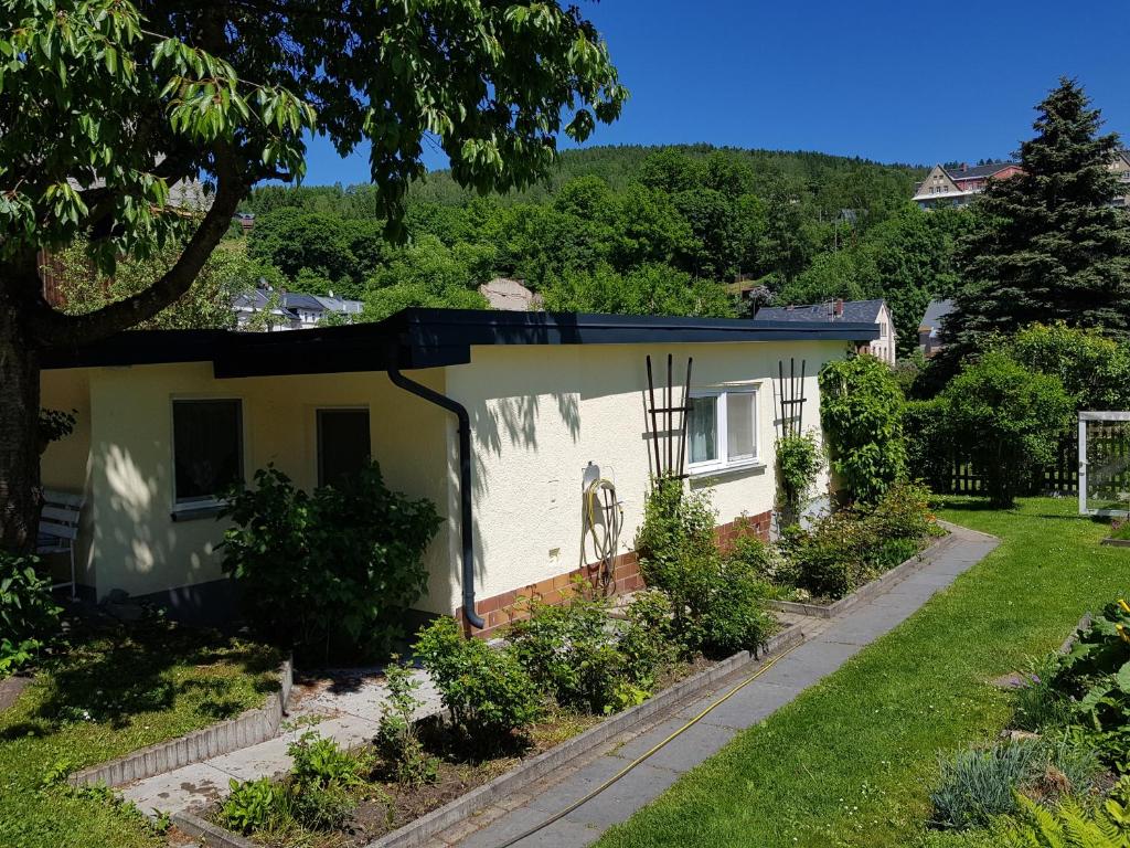 une petite maison blanche avec un jardin dans l'établissement Ferienhaus Gampe, à Klingenthal