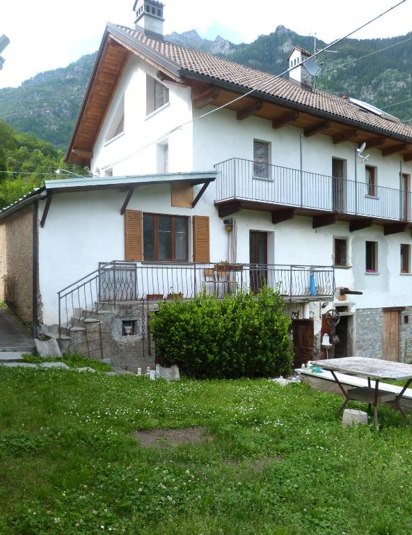 a white house with a balcony and a yard at Maison à la coque in Baceno