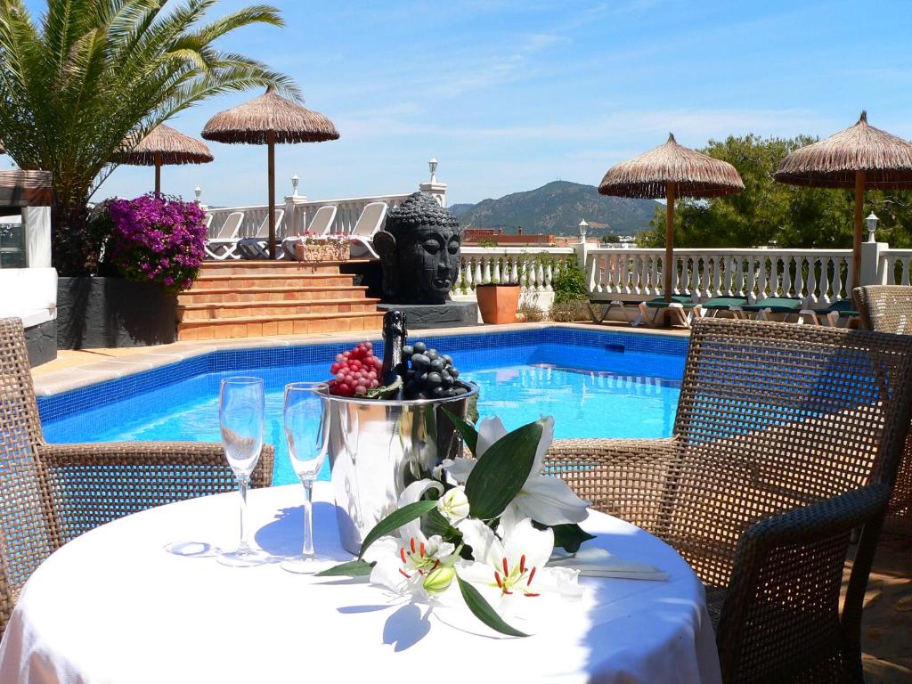 a table with wine glasses and flowers on it next to a pool at Hotel Boutique Bon Repos - Adults Only in Santa Ponsa