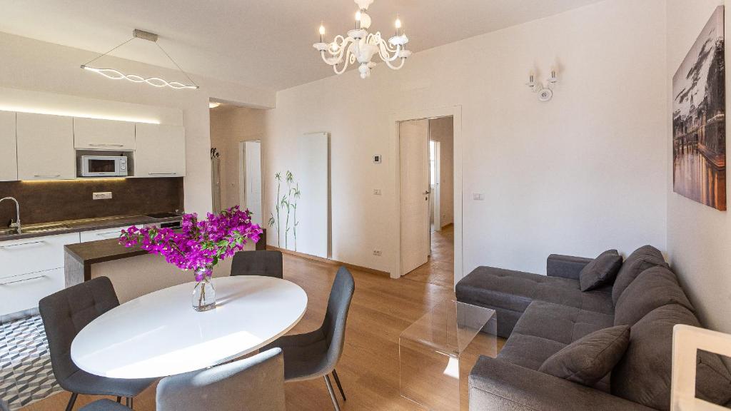 ein Wohnzimmer mit einem Sofa und einem Tisch mit lila Blumen in der Unterkunft Karan's Aparment Rental in Rome in Rom