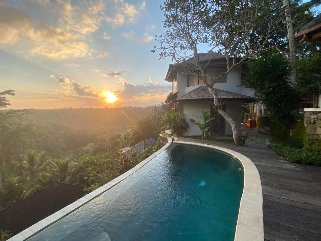 una piscina frente a una casa con puesta de sol en Villa Dhyan, en Ubud